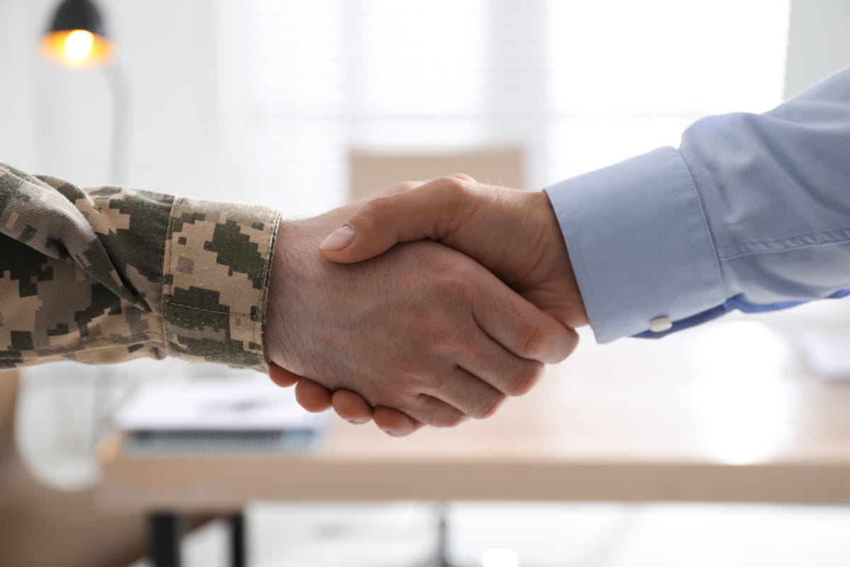 A business person and a soldier shaking hands
