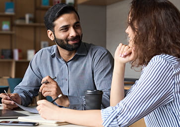 Two people speaking while taking notes